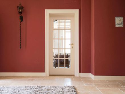 Zona d'ingresso con piastrelle in travertino e pareti rosse