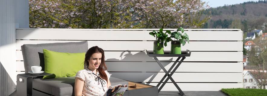 Donna seduta su una terrazza con piastrelle grigie effetto ardesia e mobili moderni
