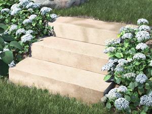 Gradini a blocco in pietra calcarea di Camino Sand con fiori e arbusti