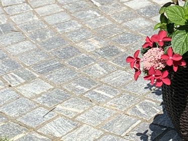 Galleria 1: Sampietrini in gneiss della linea Urban Grey Line immerse nel verde e circondate da fiori