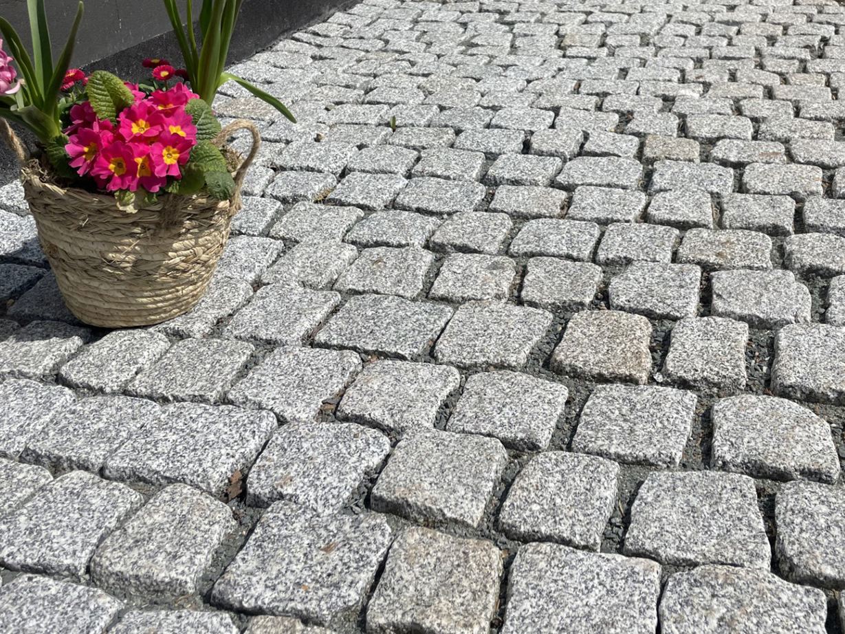 I Sampietrini chiari hanno un aspetto moderno con un tocco rustico. Foto del cliente Pavimentazione_in_pietra_granito Argento_Rustice_driveway_vicino_ai_fiori