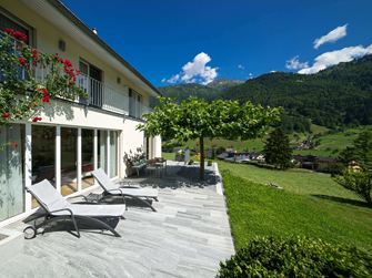 Terrazza con lastre di granito, sedie a sdraio e montagne sullo sfondo