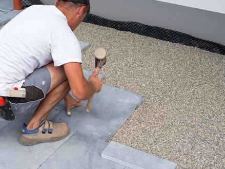 L'uomo posa lastre di pietra azzurra in un letto di pietrisco