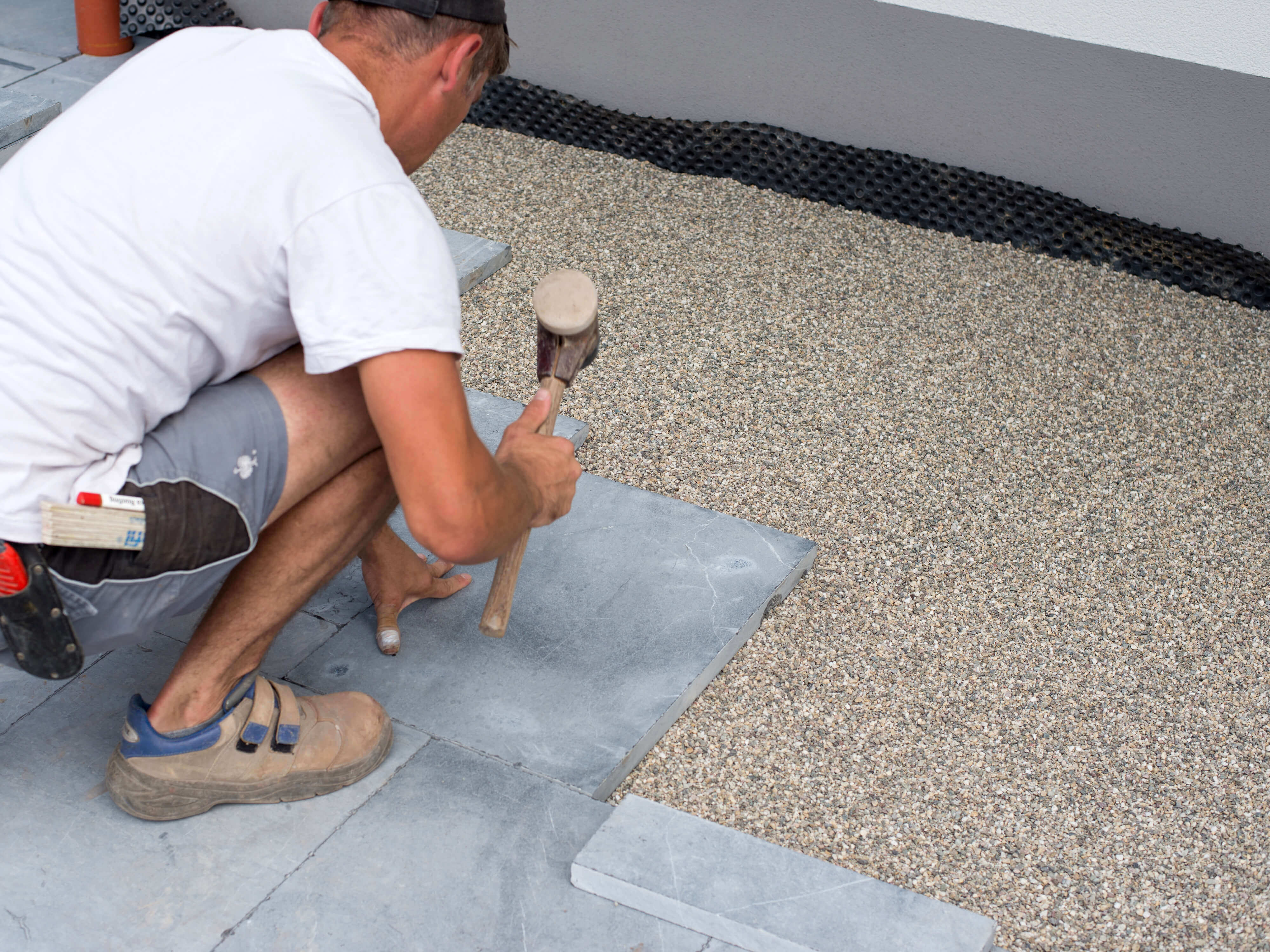 L'uomo posa lastre di pietra azzurra in un letto di pietrisco