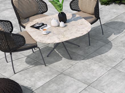 Terrazza con sedia e poltroncine, pavimento in piastrelle di gres porcellanato di colore chiaro con effetto cemento