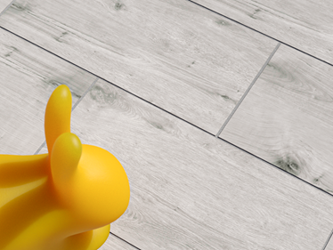 Vista dall'alto del pannello effetto legno Amber Oak con coniglietto di gomma giallo