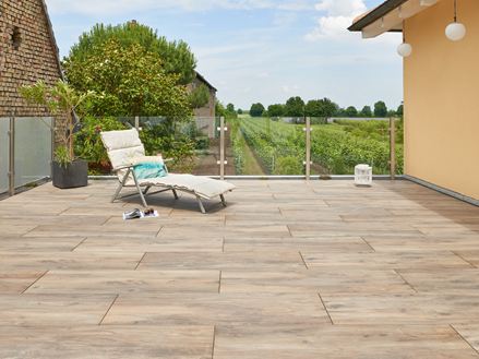 Una sedia a sdraio su una terrazza con pavimento in legno, con un vigneto sullo sfondo