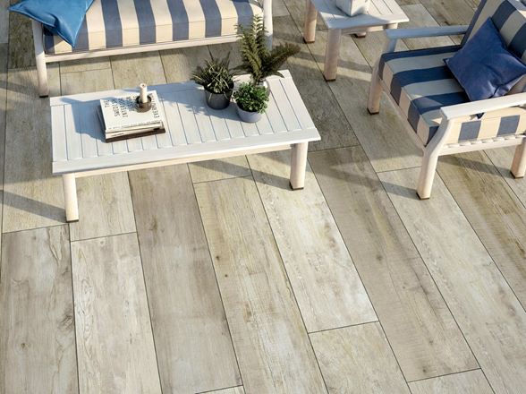 Terrazza con mobili da giardino bianchi e pannelli effetto legno fotografata dall'alto