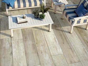 Terrazza con mobili da giardino bianchi e pannelli effetto legno fotografata dall'alto
