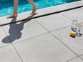 I piedi camminano a piedi nudi sul Bordo piscina realizzato con piastrelle in gres porcellanato Alpine Grey