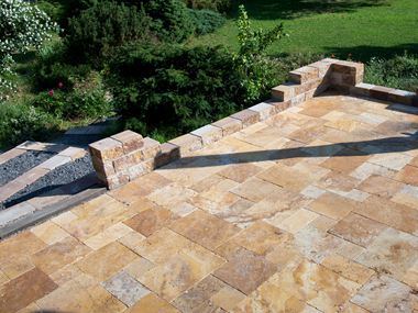 Lastra di travertino Gold posata a legaccio romano con muro in pietra naturale e giardino adiacente