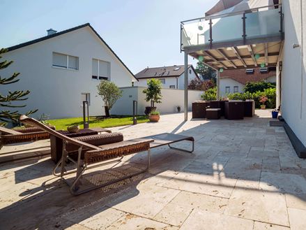 Terrazza soleggiata con due lettini e pavimento in travertino di Medium.