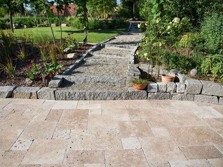 Terrazza con travertino del Noce in primo piano, bordatura in granito, giardino sullo sfondo
