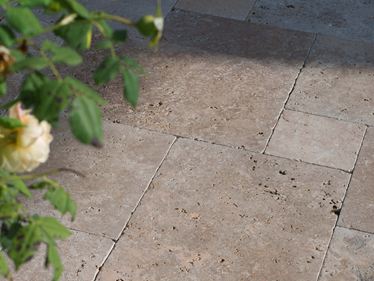 Il sole del tardo pomeriggio gioca sul pavimento della terrazza, i rami sporgono nell'immagine da destra