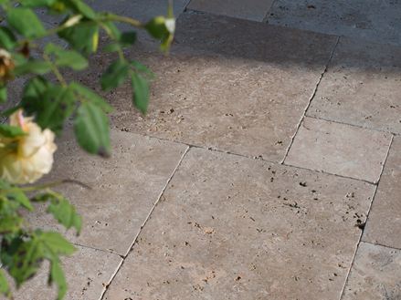 Il sole del tardo pomeriggio gioca sul pavimento della terrazza, i rami sporgono nell'immagine da destra