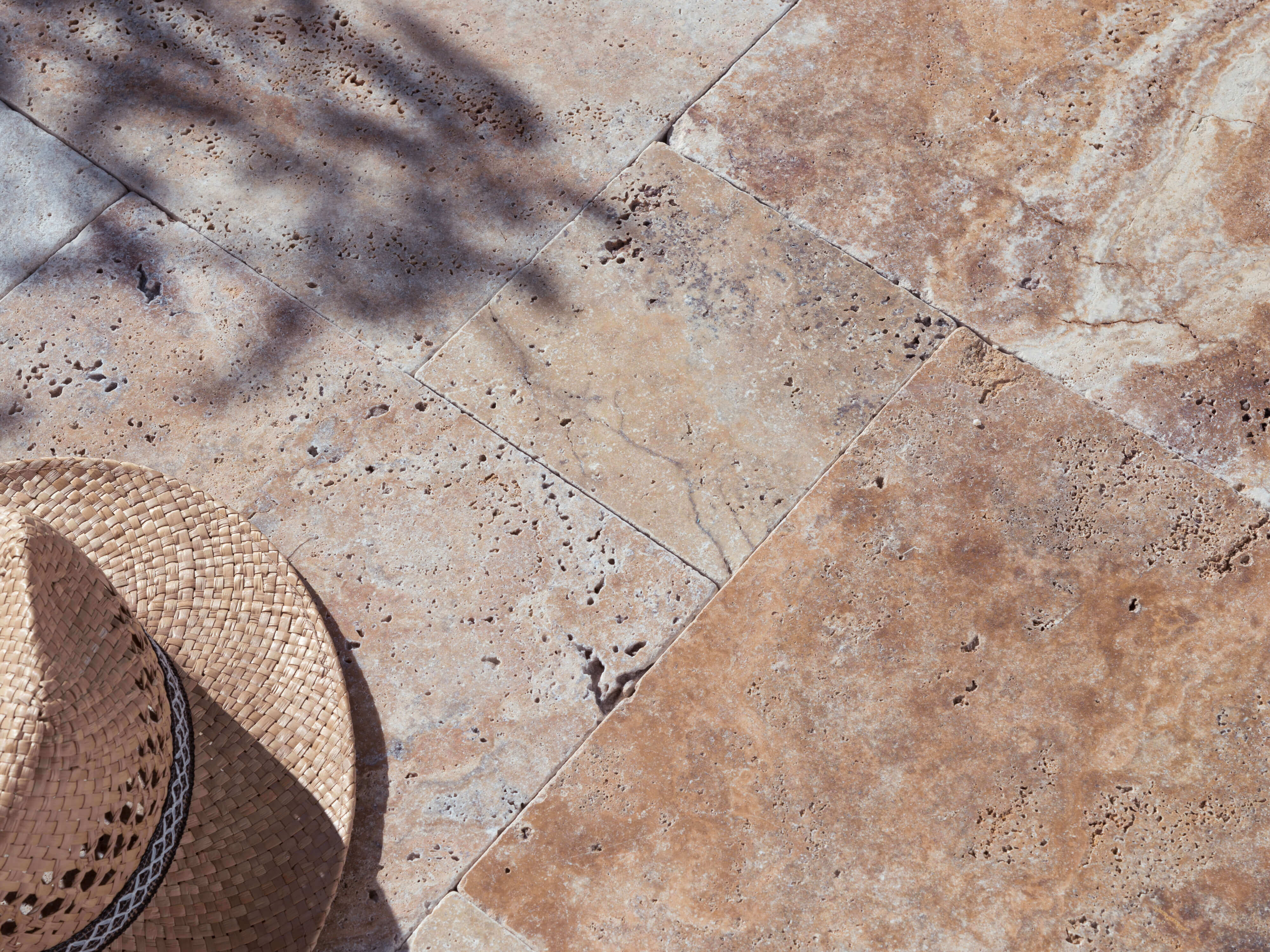 Terrazza di Scabas in travertino alla luce del sole con cappello di paglia