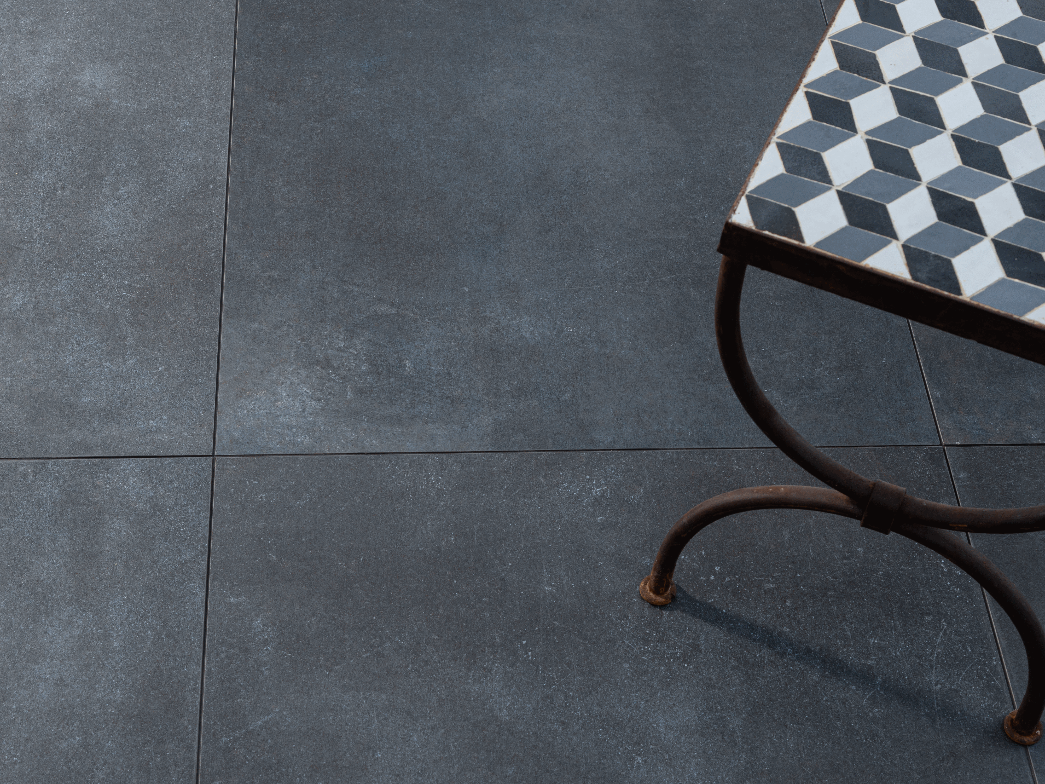 Piastrelle scure effetto cemento con tavolino fotografato dall'alto