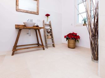 Bagno con mobili in legno e pavimento in piastrelle di calcare naturale di colore chiaro