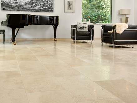 Soggiorno luminoso con pavimento in pietra calcarea beige, divani moderni e pianoforte a coda.