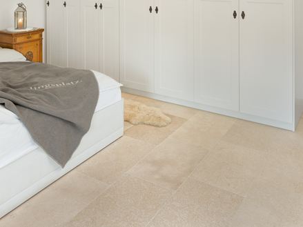 Camera da letto con armadio bianco e letto bianco, pavimento in piastrelle di calcare beige.