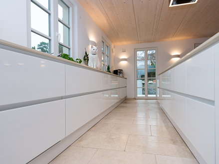 Cucina a vista con piastrelle in pietra calcarea Cleopatra Light e mobili da cucina bianchi