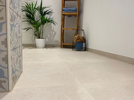 Bagno moderno con mobili in legno, piante decorative e Piastrelle chiare dall'aspetto calcareo