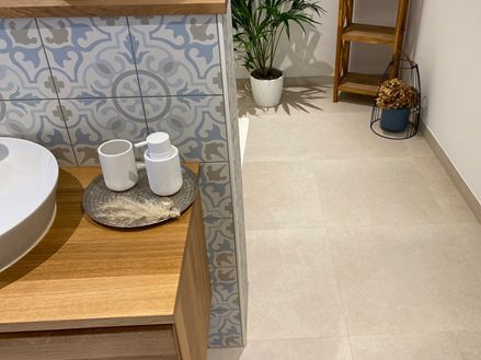 Bagno con elementi in legno e piante decorative, Piastrelle Sevilla Cream effetto calcare come pavimento