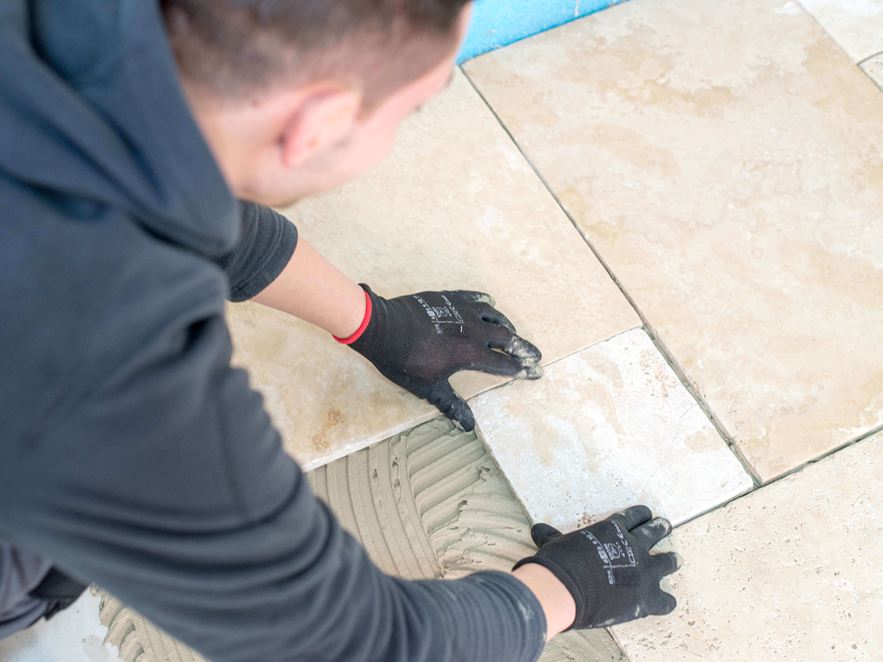 L'uomo posa le piastrelle in travertino beige chiaro nel vincolo romano