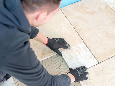 L'uomo posa le piastrelle in travertino beige chiaro nel vincolo romano