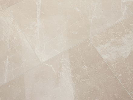 Piastrella in marmo Burdur Cream posata con superficie lucida e venature bianche nella zona di fondo beige