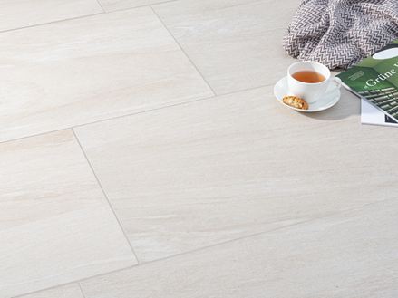 Piastrelle beige chiaro effetto pietra con sopra una tazza di caffè e una coperta