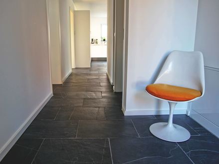 Foto cliente: Piastrelle in ardesia Black Rustic nel corridoio con poltrona bianca in primo piano