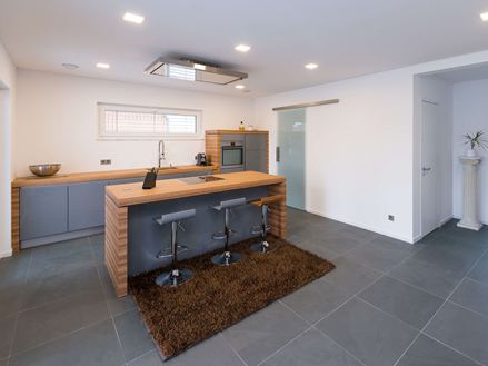 Cucina con elementi in legno e piastrelle in ardesia di colore grigio tenue come pavimento