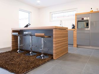 Cucina con bancone bar aperto, elementi moderni in legno e pavimento in ardesia scura