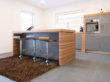 Cucina con bancone bar aperto, elementi moderni in legno e pavimento in ardesia scura