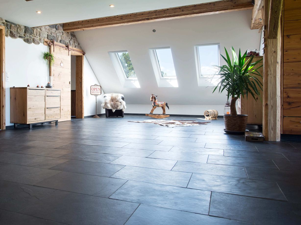 Camera con pavimento in ardesia color antracite e mobili in legno, pareti bianche