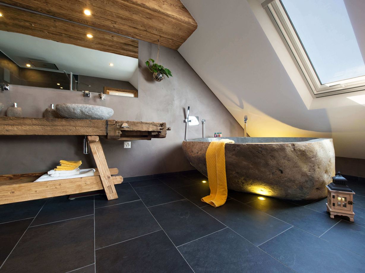 Bagno rustico con vasca da bagno in pietra e pavimento in piastrelle di ardesia scura