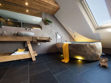 Bagno rustico con vasca da bagno in pietra e pavimento in piastrelle di ardesia scura