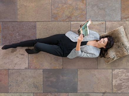 Donna sdraiata su piastrelle di ardesia colorate Peacock Multi Color e lettura