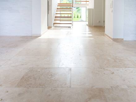 Ampio spazio con piastrelle in travertino di colore beige chiaro, una scala sullo sfondo
