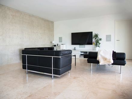 Soggiorno moderno con divano nero e pavimento in piastrelle di travertino Classic Light di colore beige chiaro