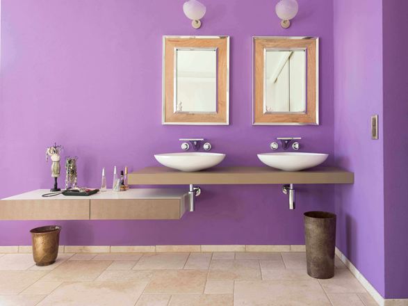 Bagno con parete viola e due specchi su piastrelle di travertino Light con superficie burattata
