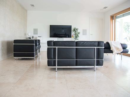 Soggiorno con Piastrelle Classic Light di Travertin e divano moderno nero