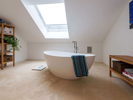 Bagno con Medium Line in travertino, vasca da bagno indipendente e asciugamano