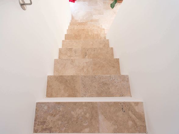Scala con pareti bianche e travertino Medium come pedata