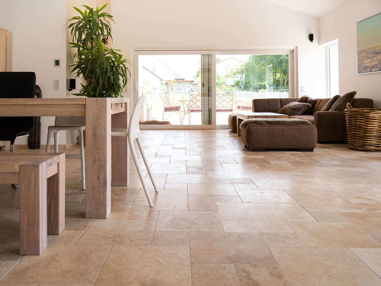 Soggiorno con divano marrone, pareti bianche e pavimento in piastrelle di travertino Medium marrone-beige