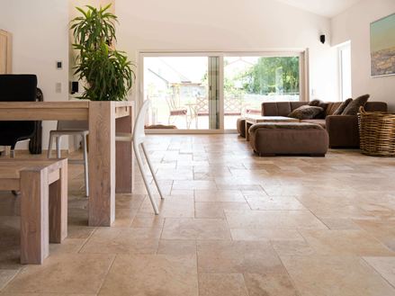 Soggiorno con divano marrone, pareti bianche e pavimento in piastrelle di travertino Medium marrone-beige