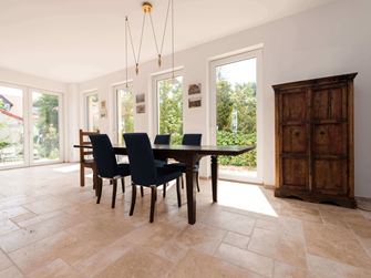 Soggiorno e sala da pranzo con arredi rustici e piastrelle in travertino