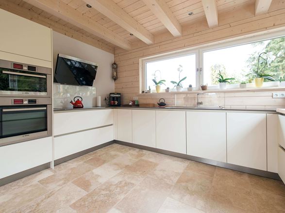 Cucina con mobili bianchi e pavimento in piastrelle di travertino rustico di colore beige