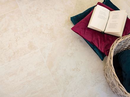 Piastrelle effetto travertino con cuscini e un libro aperto